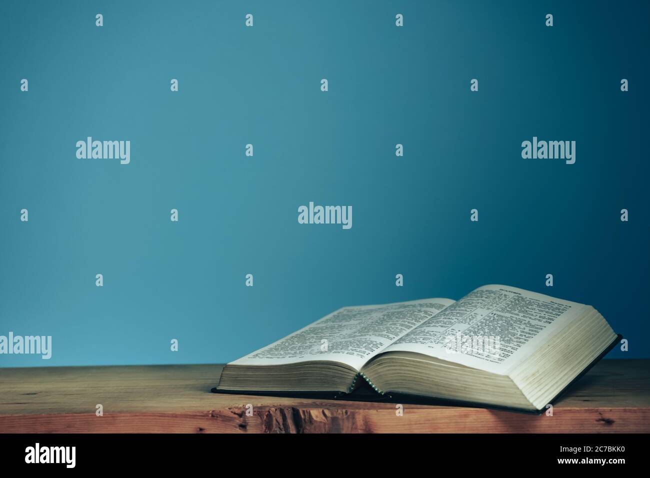 Open Holly Bible on a red wooden table. Beautiful blue wall background ...
