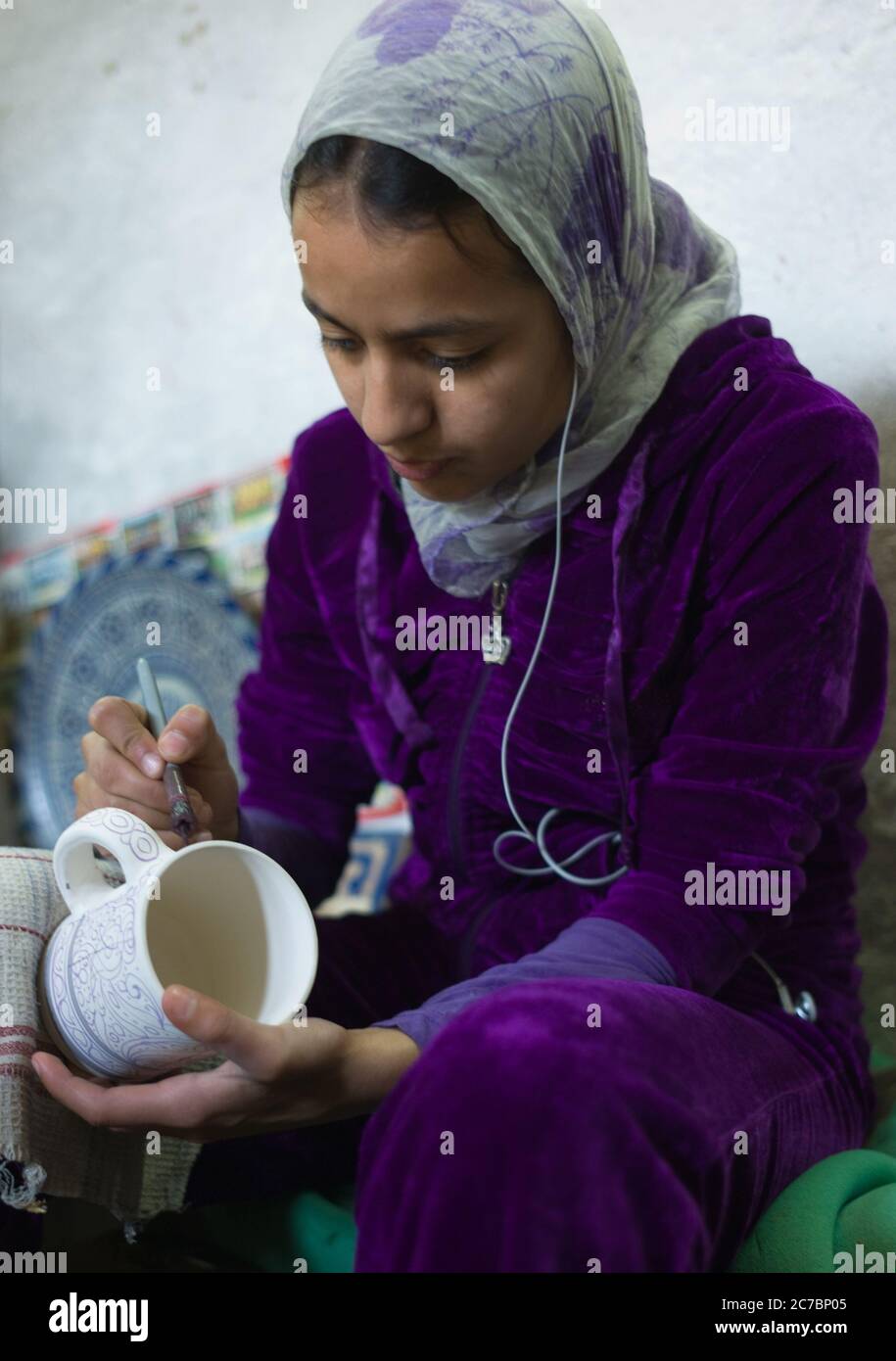 Moroccan girl with a headscarf paints a bowl in a pottery factory in Fes, Morocco. Stock Photo