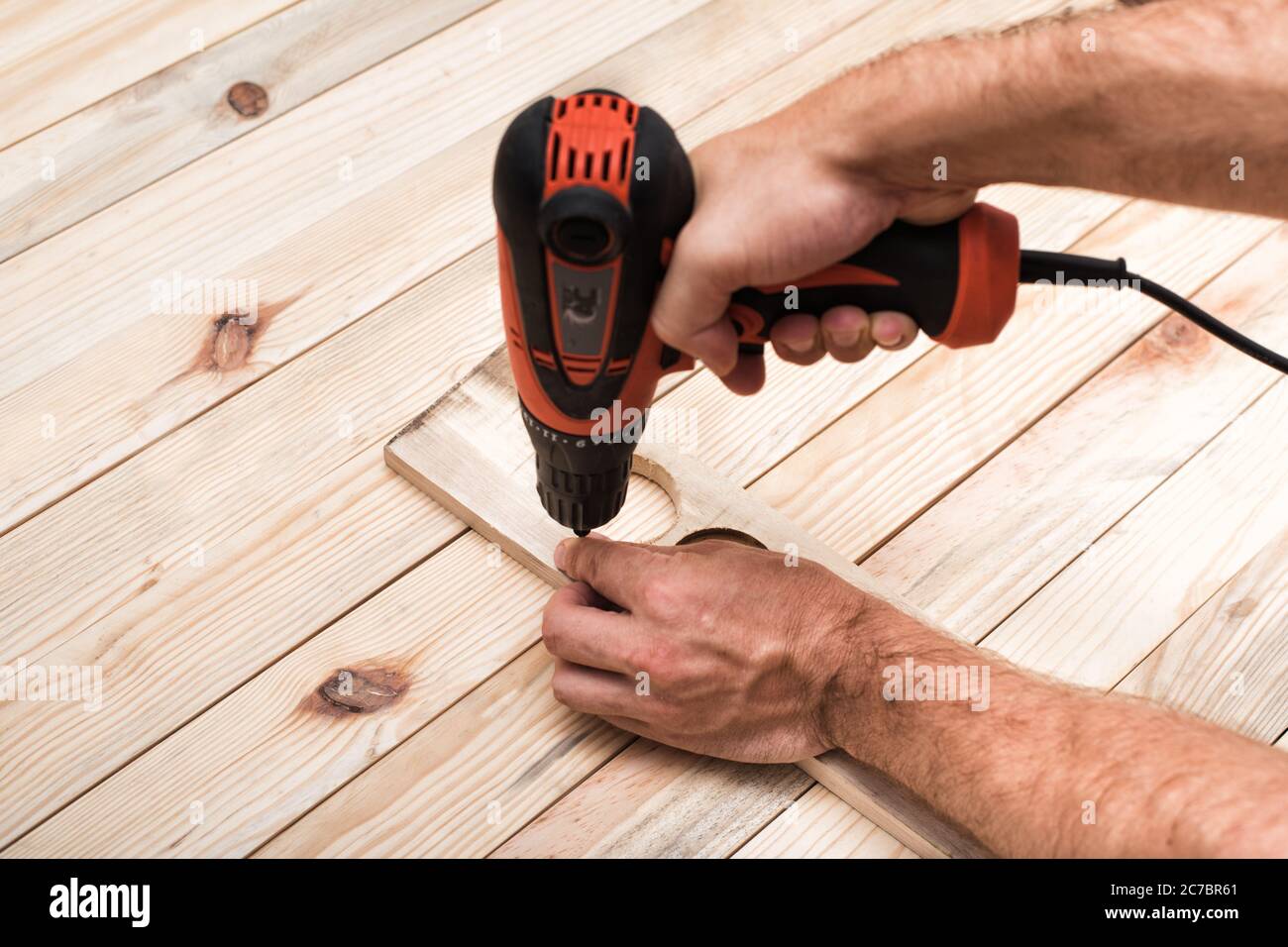 Electric drill screwdriver in male hand. Tightening screw, processing