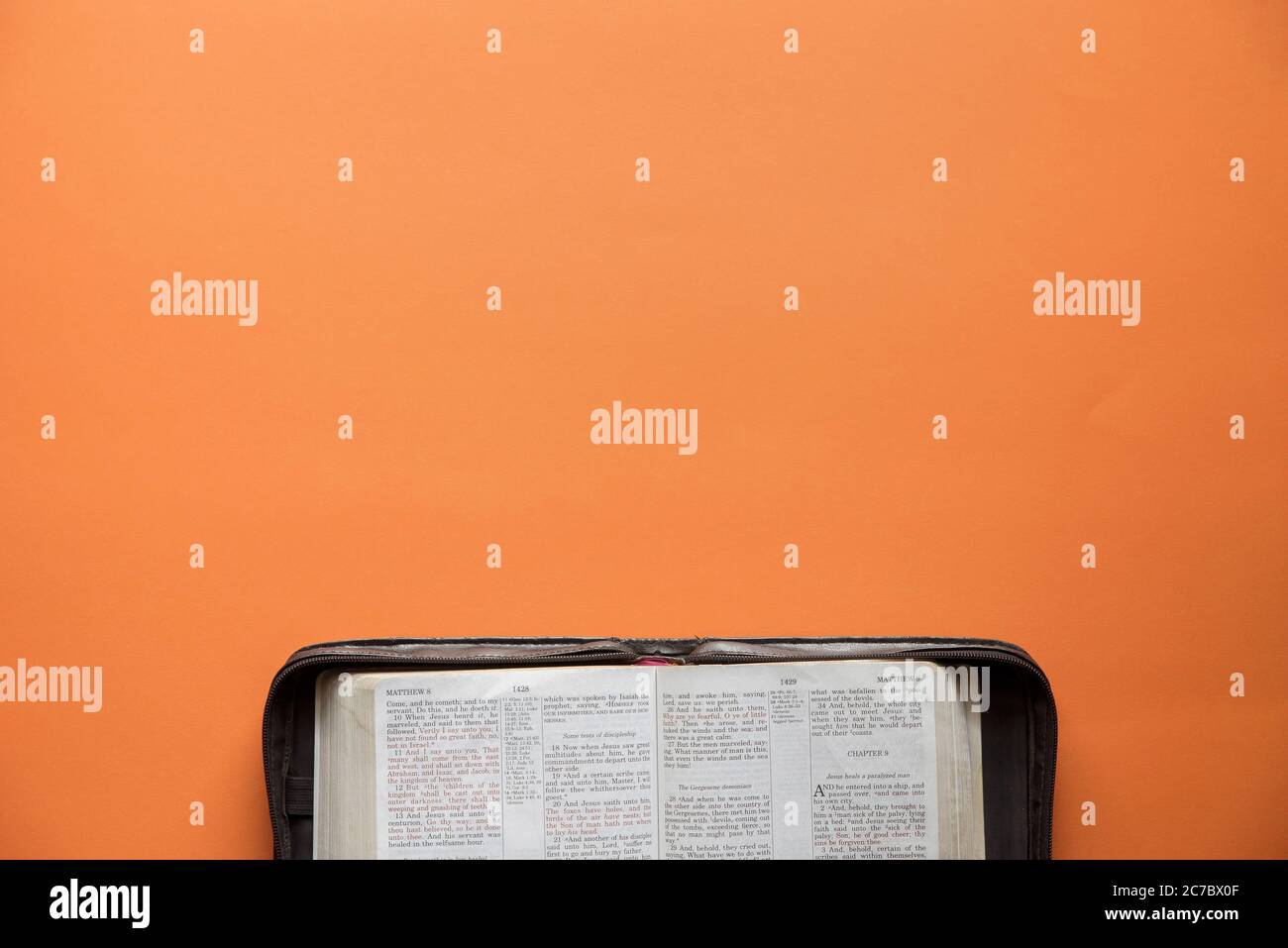 Overhead shot of an open book on an orange surface Stock Photo