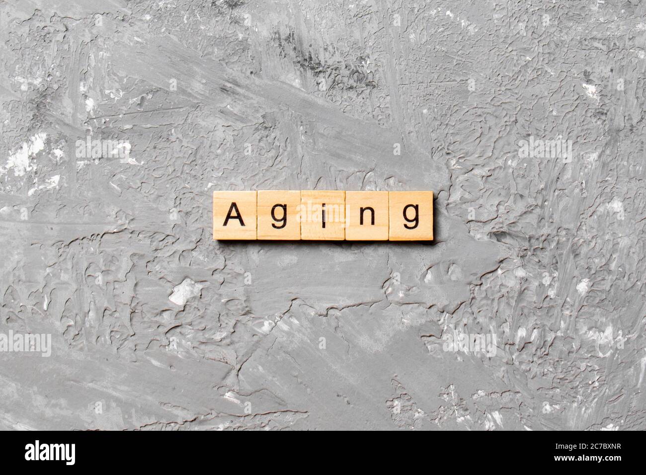 Aging word written on wood block. Aging text on cement table for your