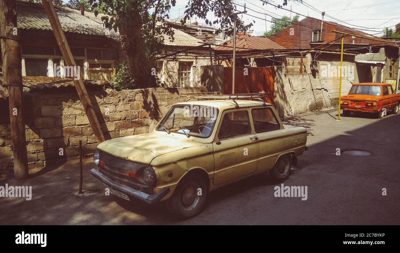 Horizontal shot of an old white car and an old red car in a village in ...