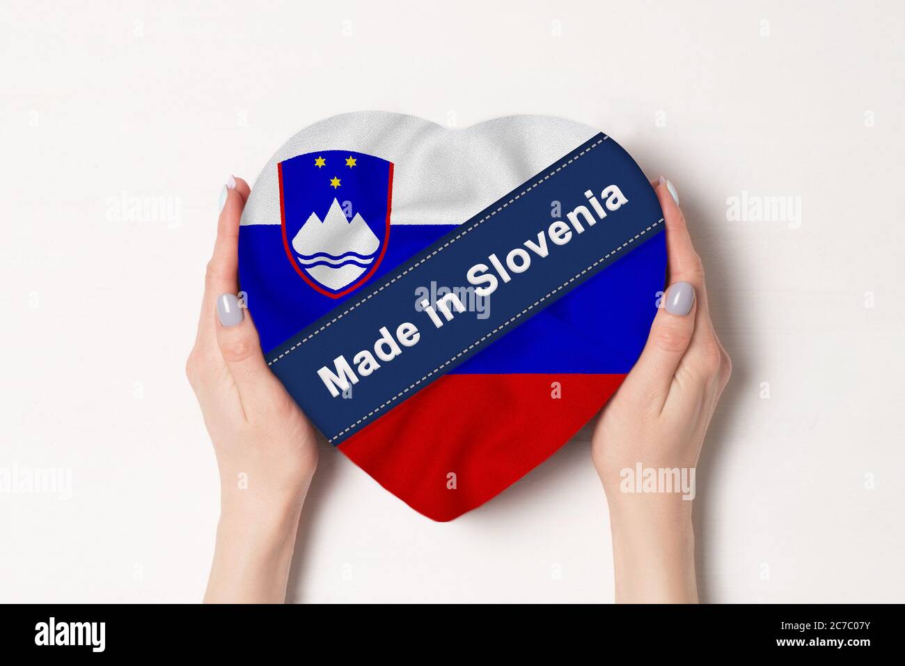 Inscription Made in Slovenia the flag of Slovenia. Female hands holding a heart shaped box. White background. Stock Photo