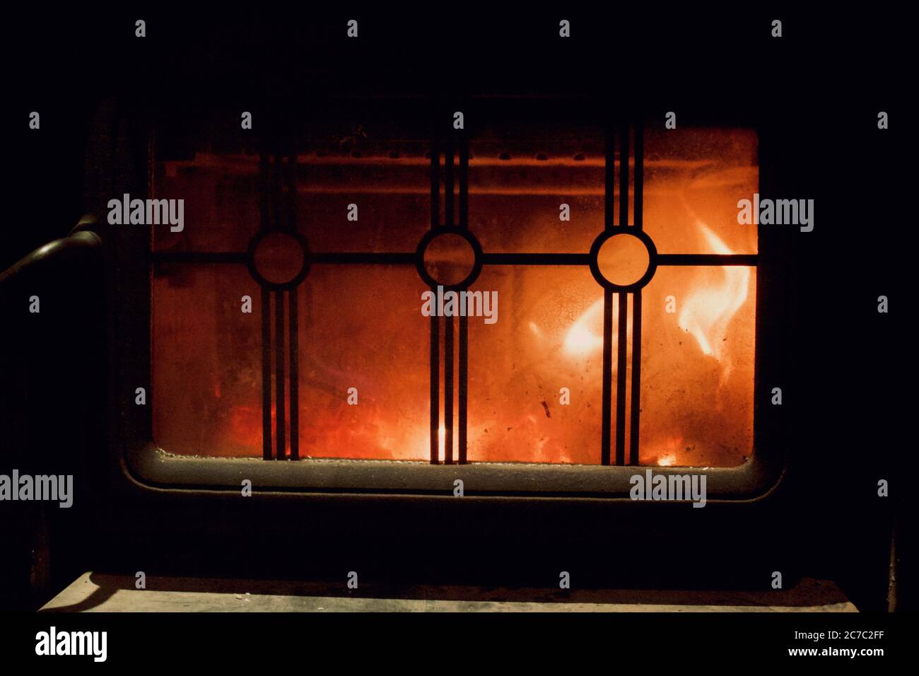 Closeup shot of fire burning in a fireplace with a metallic fence Stock Photo