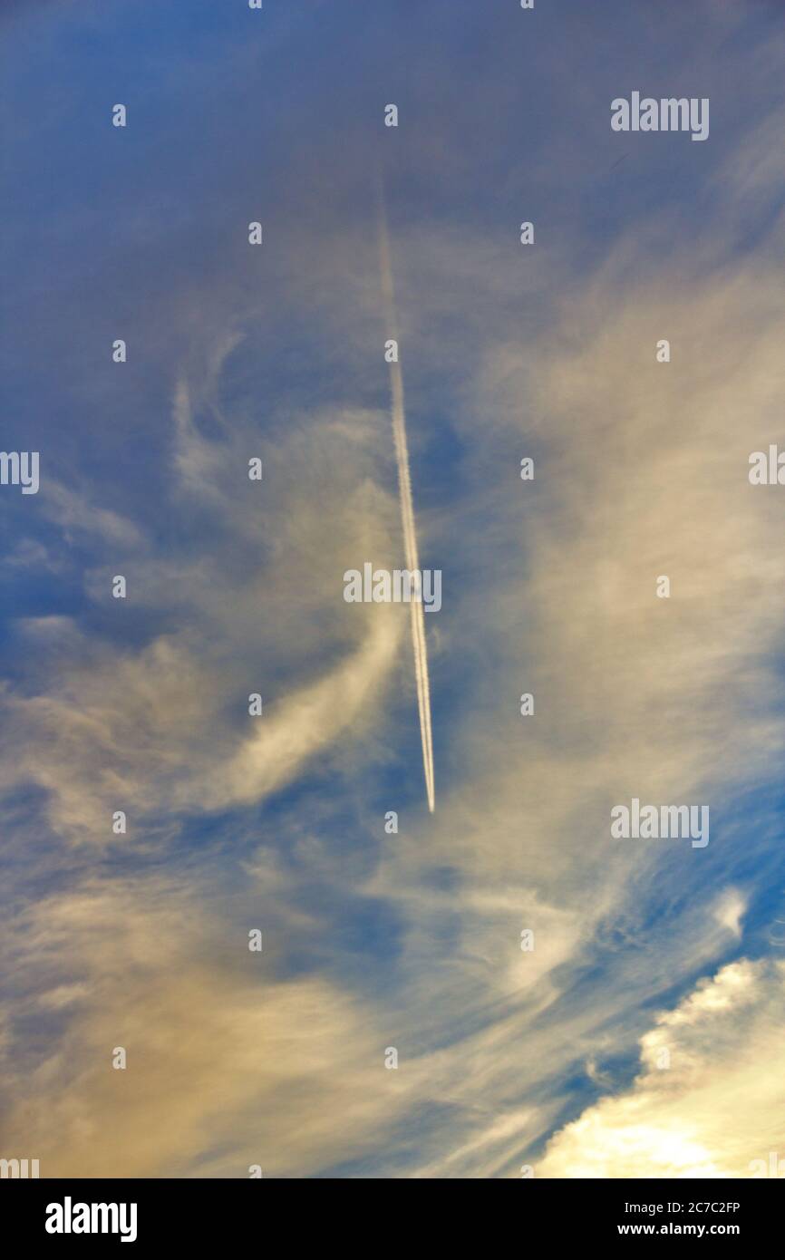Vertical shot of the blue sky with an airplane flying through clouds ...