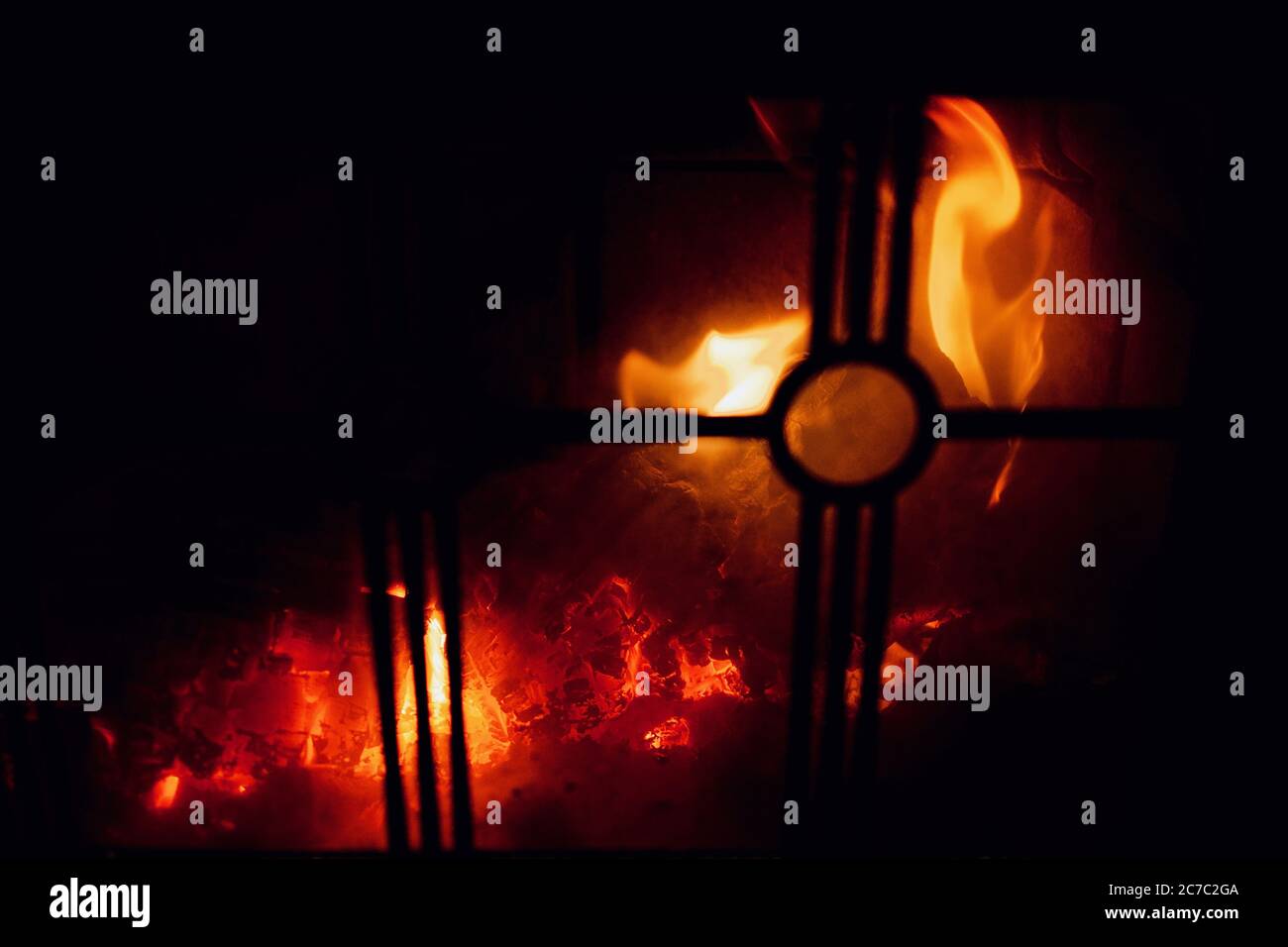 Closeup shot of fire burning in a fireplace with a metallic fence Stock Photo