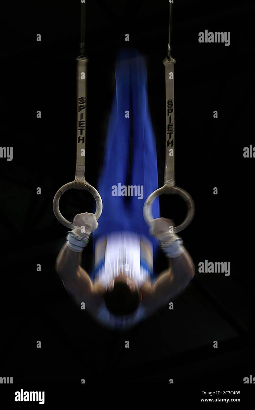 Vertical blurred shot of a male gymnast doing a flip on the gymnastic