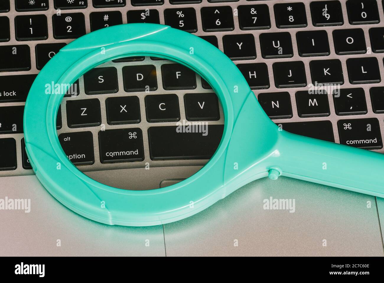 Glass magnifier on the computer keyboard. A top view of a flat layout. Stock Photo