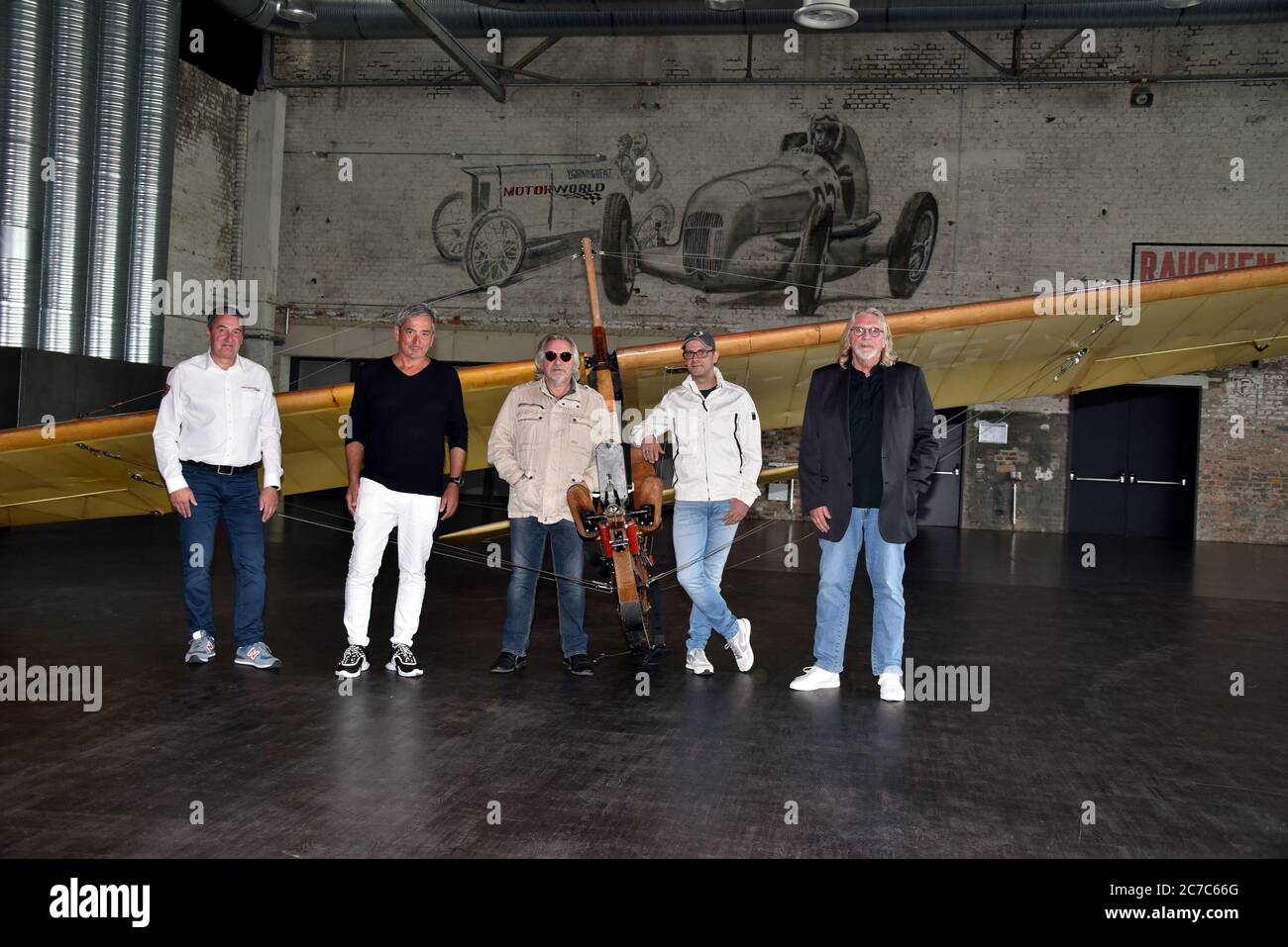 Cologne, Germany. 15th July, 2020. Dirk Strohmenger, Center- and Facility Manager at MOTORWORLD, Jürgen Walter, Catering Auftischt, musician Tommy Engel, comedian Marc Metzger and musician Jürgen Fritz pose on a school glider SG 38, glider from 1942, at the presentation of the safety and hygiene concept of the dinner show 'Weihnachtsengel' which will be shown from 20.11.2020. Credit: Horst Galuschka/dpa/Alamy Live News Stock Photo