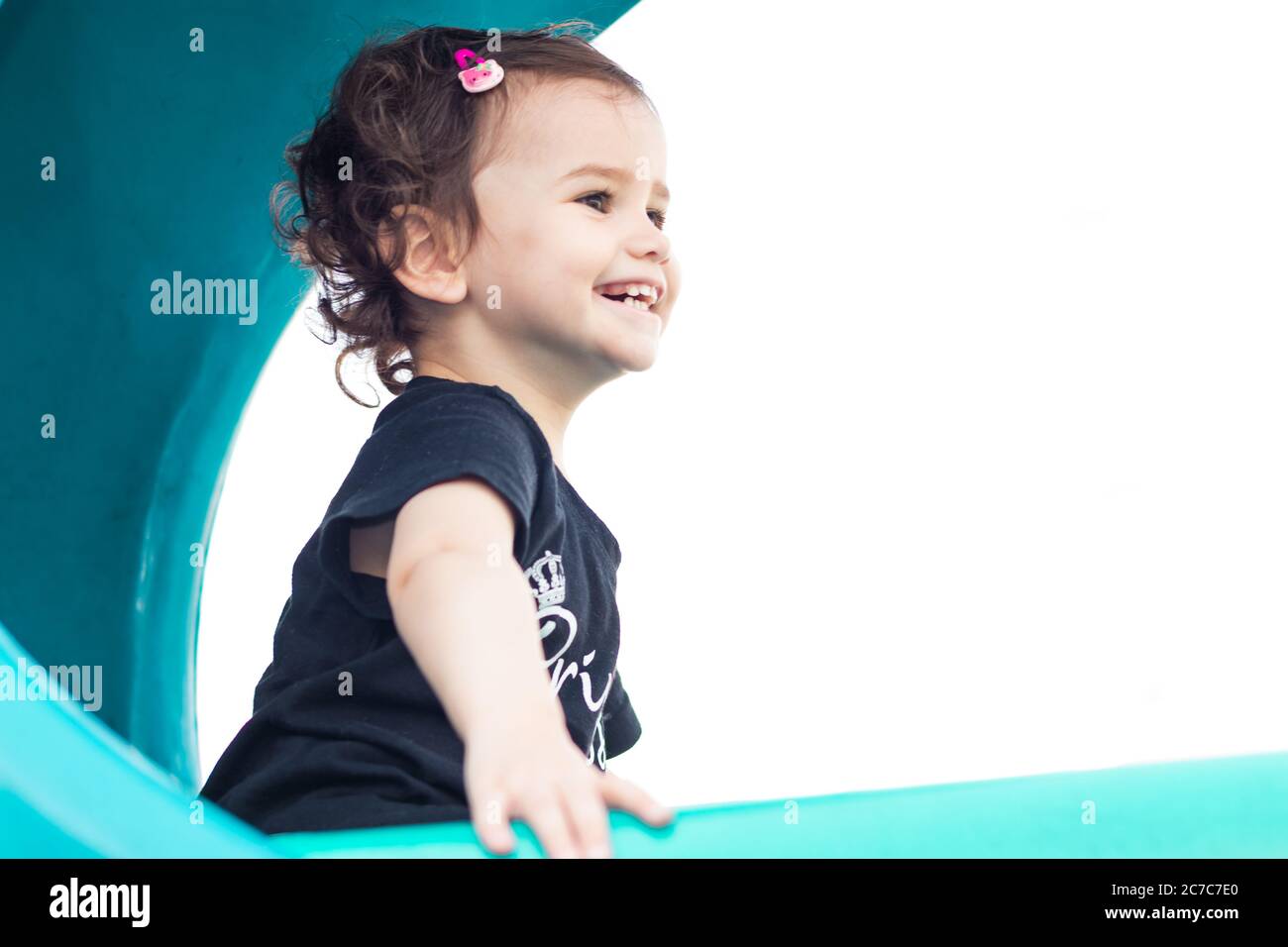 a cute little baby girl on a blue slide in a brith day. Stock Photo