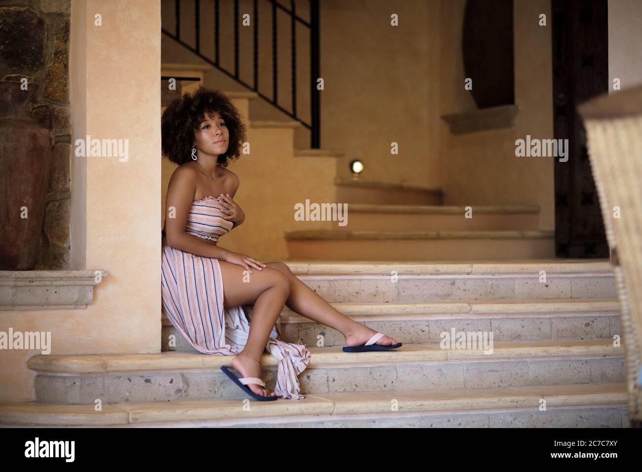 Girl of 18 years, hispanic ethnicity, sitting on stairs - Young woman with afro look hair Stock Photo