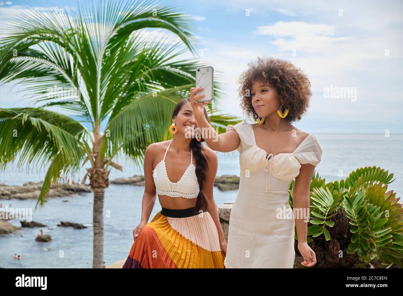 2 young women take a selfie in front of palm tree and ocean in Puerto Vallarta, Jalisco, Mexico Stock Photo