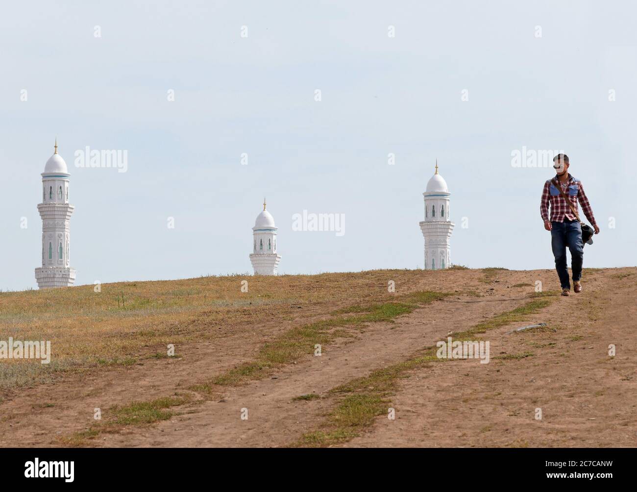 Man walking through Nur-Sultan, Kazakhstan, with minarets of a mosque in the background Stock Photo