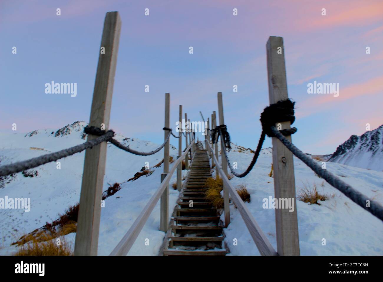 Horizontal shot of wooden stairs leading up a mountain covered in snow Stock Photo