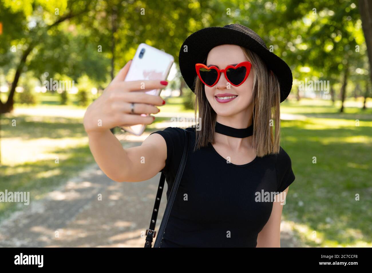 Portrait of beautiful woman makes selfie in the park Stock Photo - Alamy