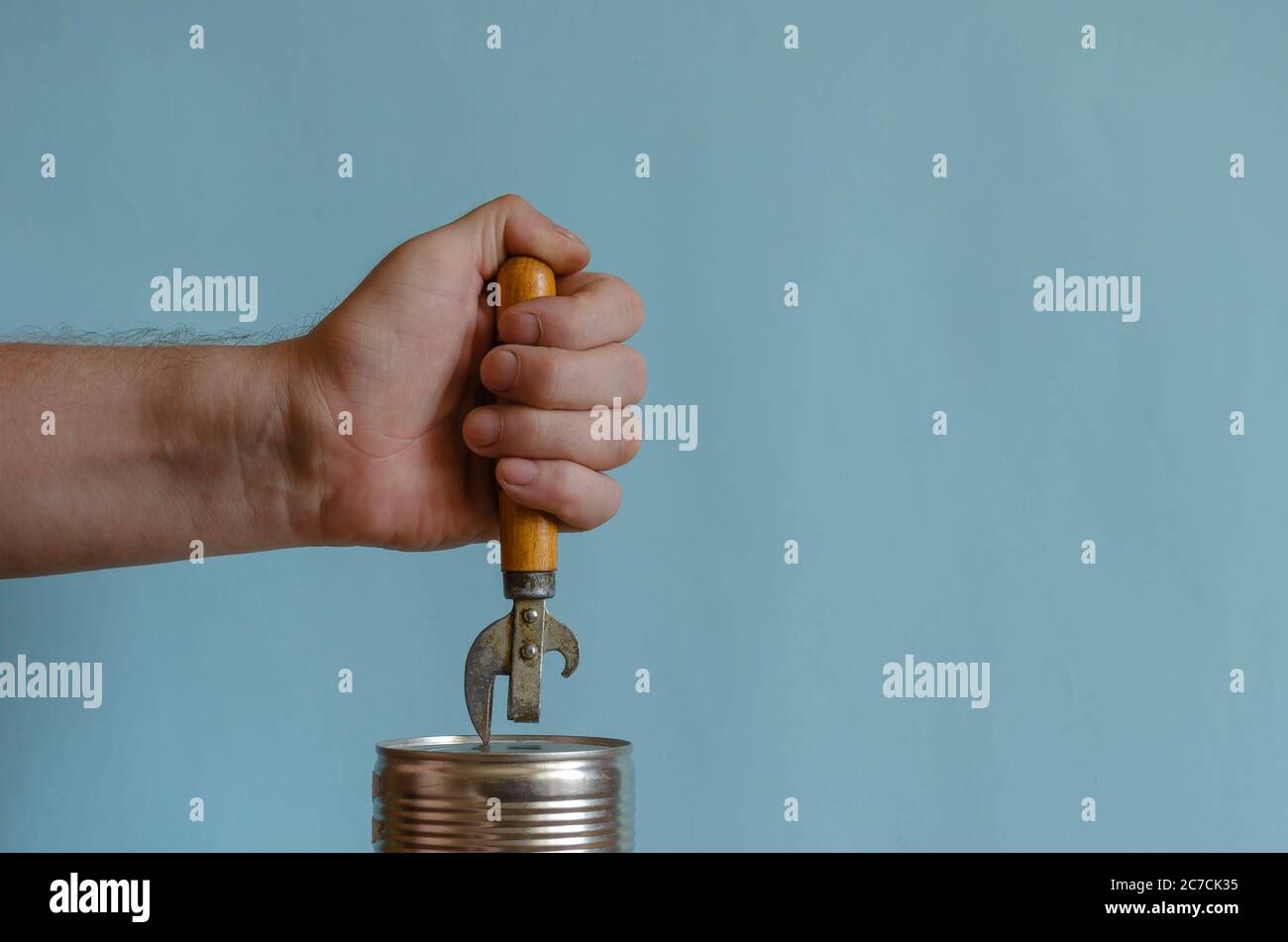 An open can and hand holding a can opener Stock Photo - Alamy