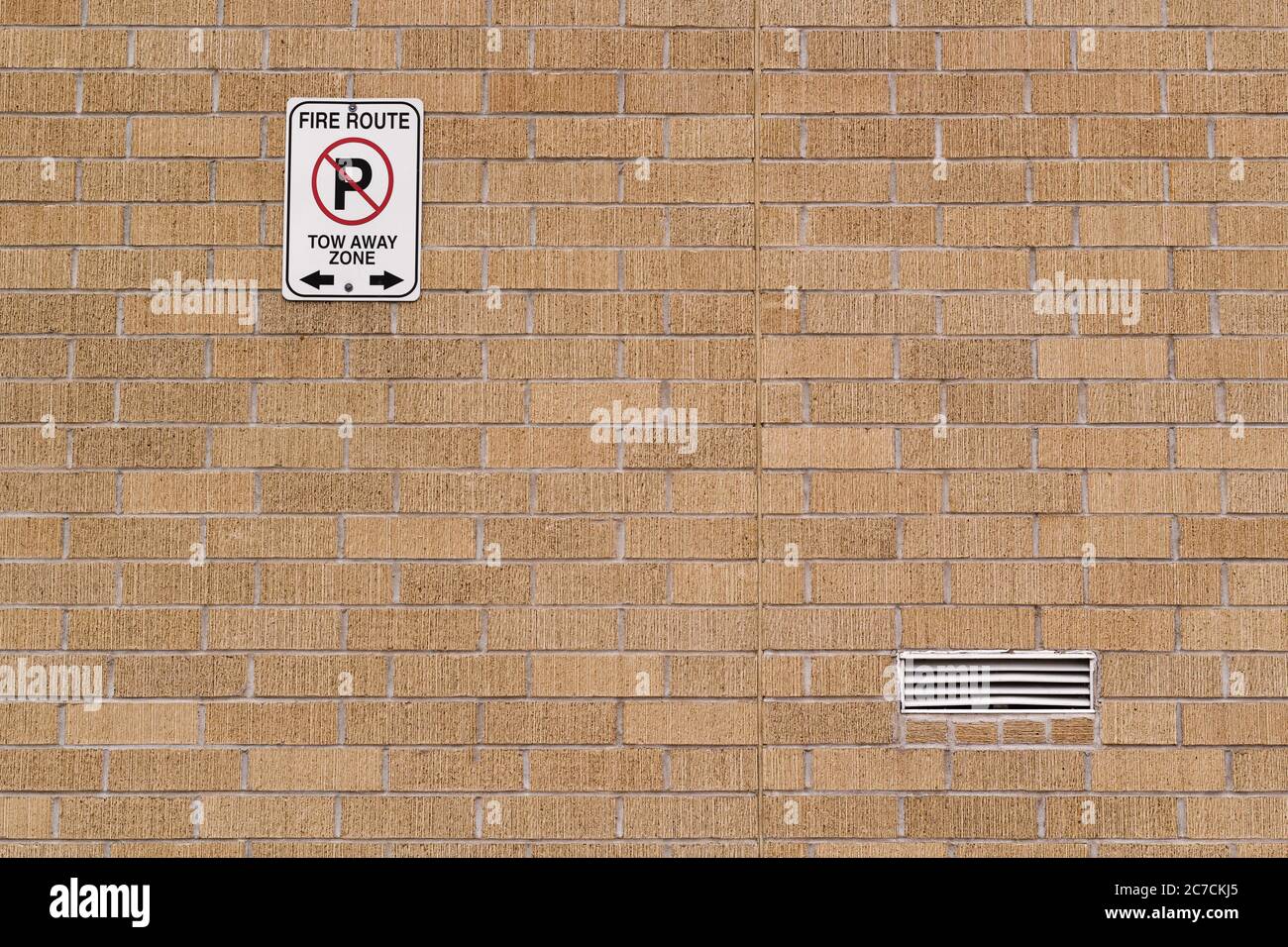 Fire route and tow away zone sign on brick wall Stock Photo