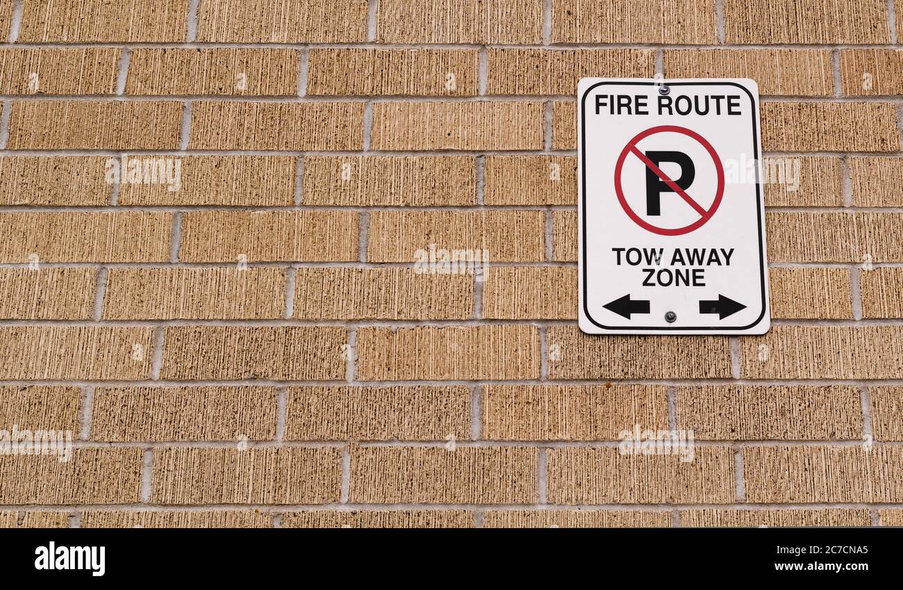 Fire route and tow away zone sign on brick wall Stock Photo
