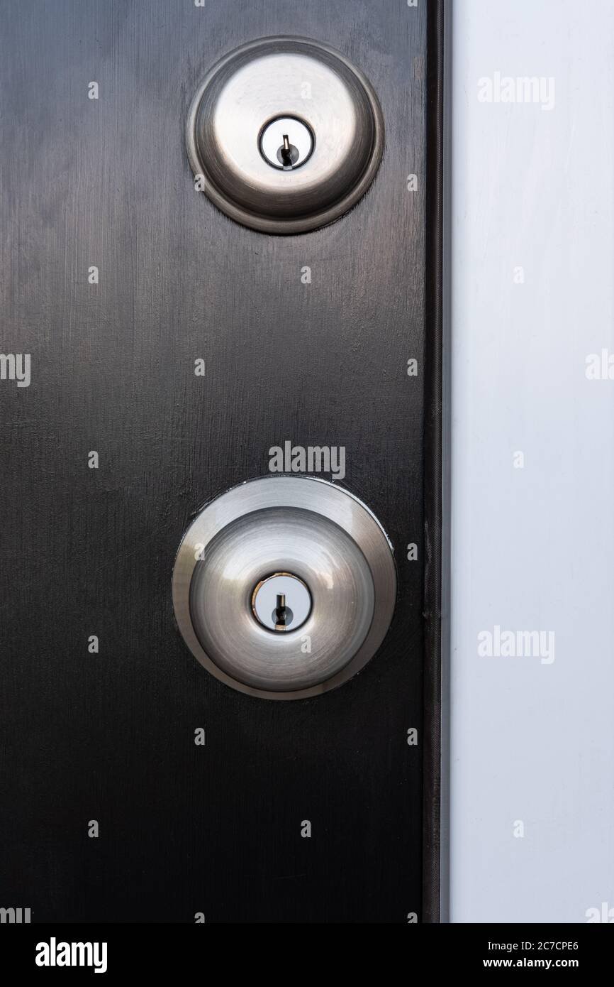 Photograph of a locking door knob and deadbolt on a black painted door with a white door jamb