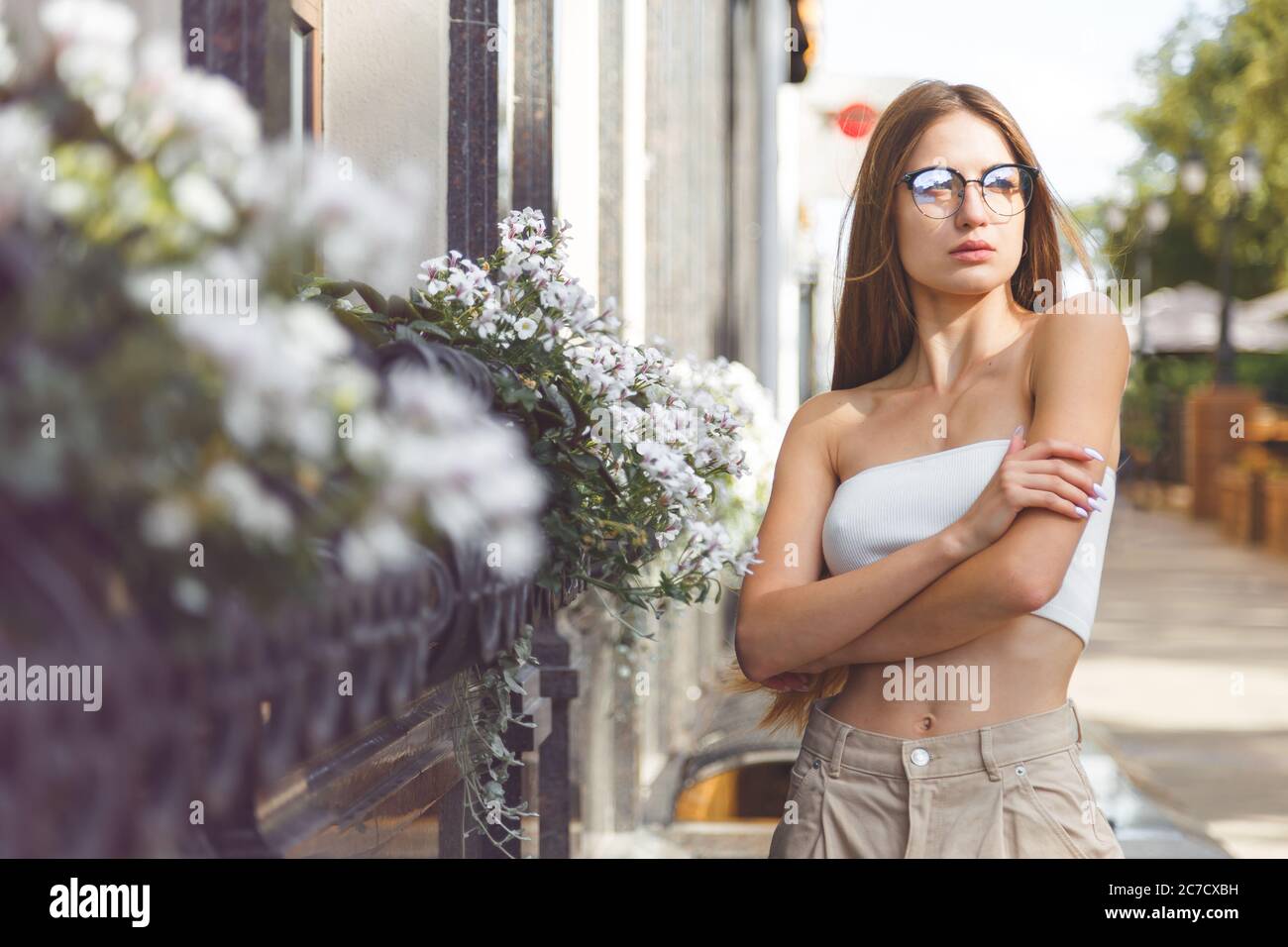 Young fashionable girl wearing eyeglasses, top, posing in street of European city. Copy, empty space for text Stock Photo