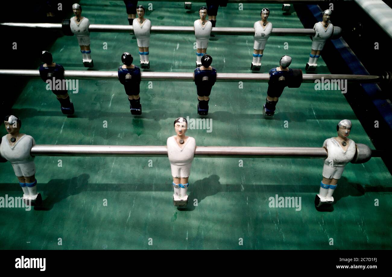 Foosball table with players in action at a lively entertainment venue during evening hours Stock Photo
