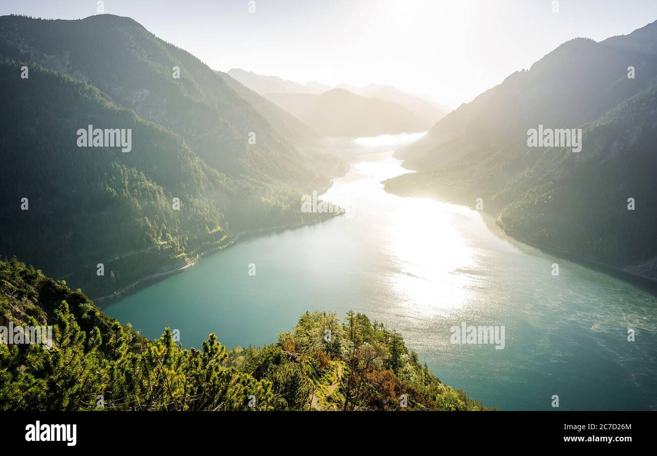 Exploring valley from top of mountain enjoying beautiful view to summer lake with turquoise water - adventure, travel and hiking concept. Plansee Stock Photo