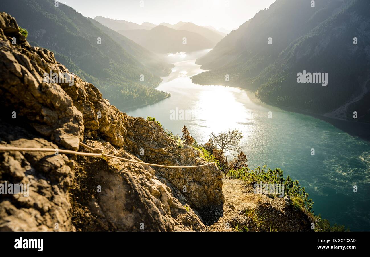 Exploring valley from top of mountain enjoying beautiful view to summer lake with turquoise water - adventure, travel and hiking concept. Plansee Stock Photo