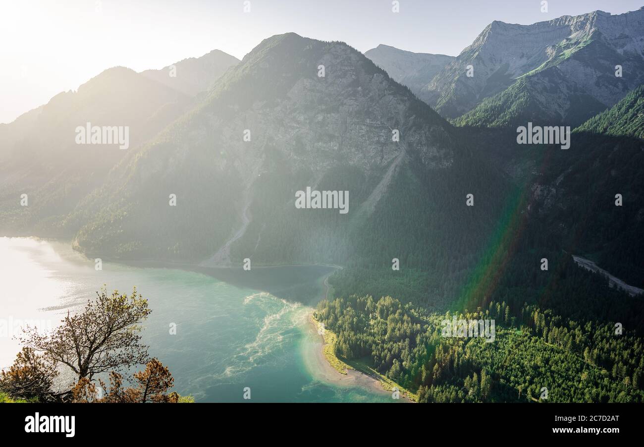 Exploring valley from top of mountain enjoying beautiful view to summer lake with turquoise water - adventure, travel and hiking concept. Plansee Stock Photo