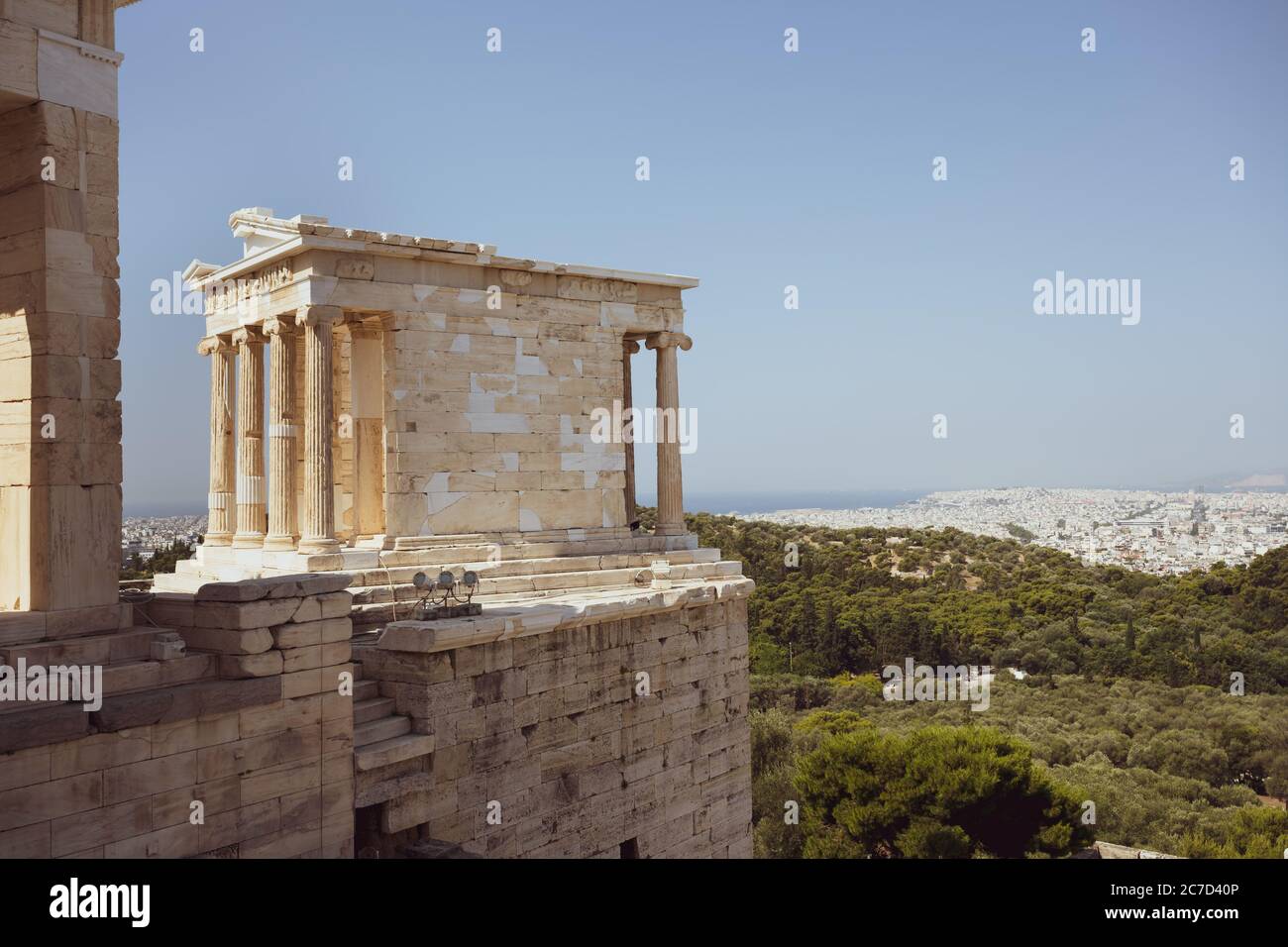 The temple of Nike on the Acropolis in Athens in Greece without people in the sunlight and blue sky with the city of Athens in background Stock Photo