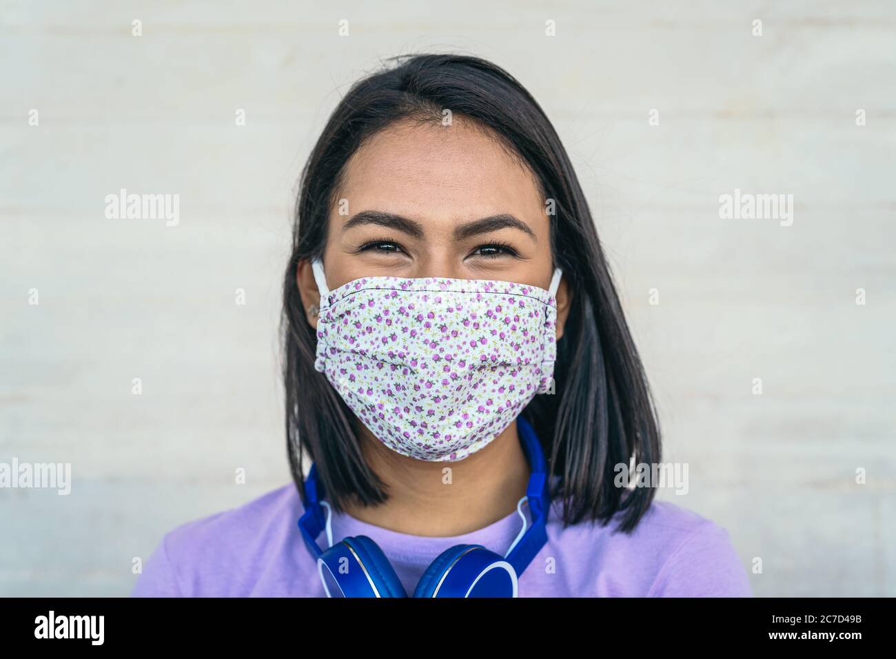 Young woman wearing face mask portrait - Latin girl using protective facemask for preventing spread of corona virus Stock Photo