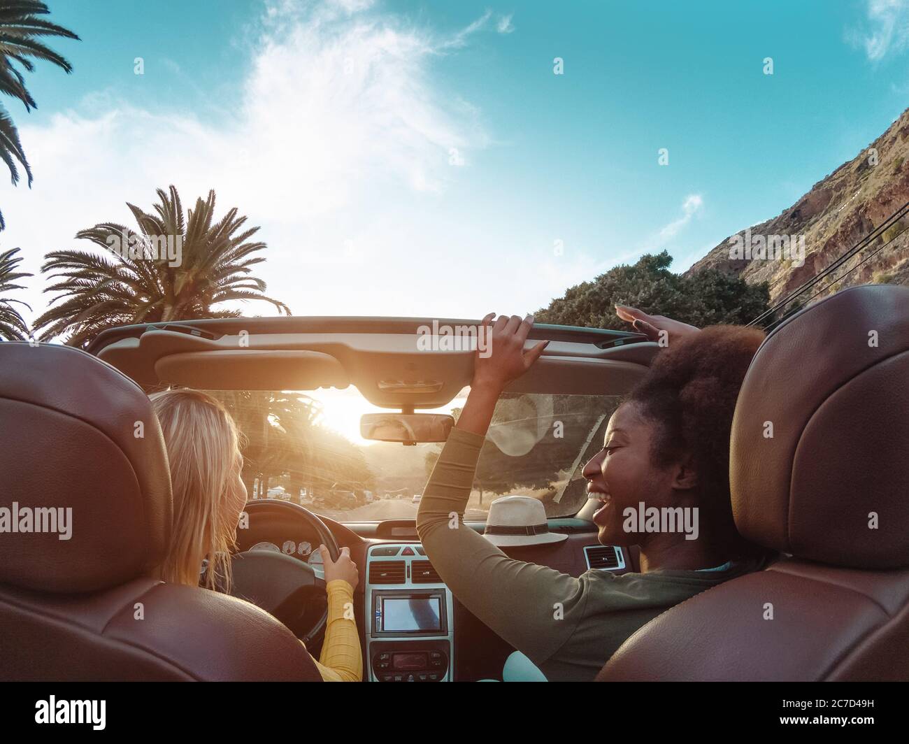 Young happy women doing a road trip in tropical city - Travel people having fun driving in trendy convertible car discovering new places Stock Photo