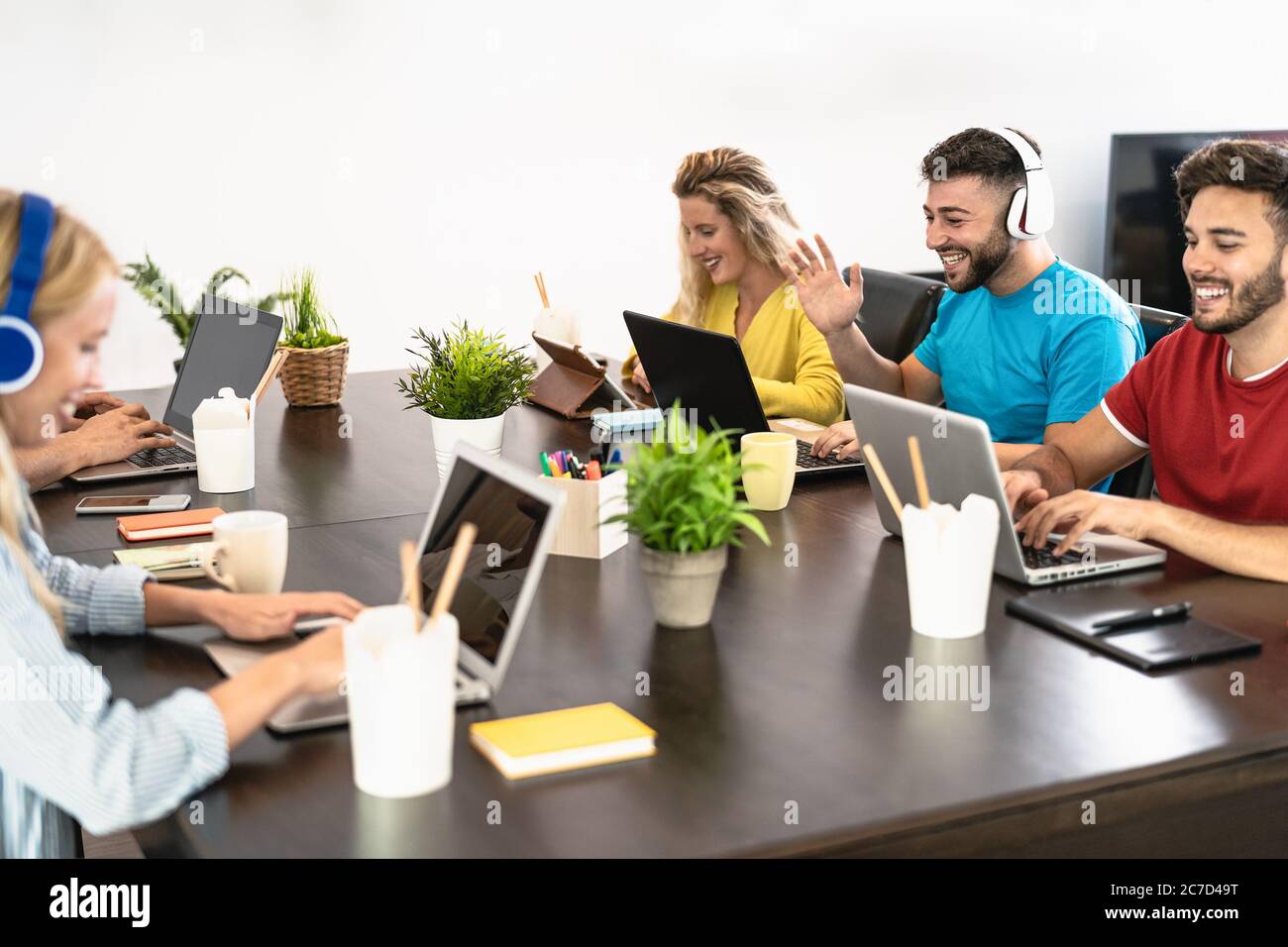 Young friends working together inside co-working creative space - Millennial people doing startup strategy in modern office Stock Photo