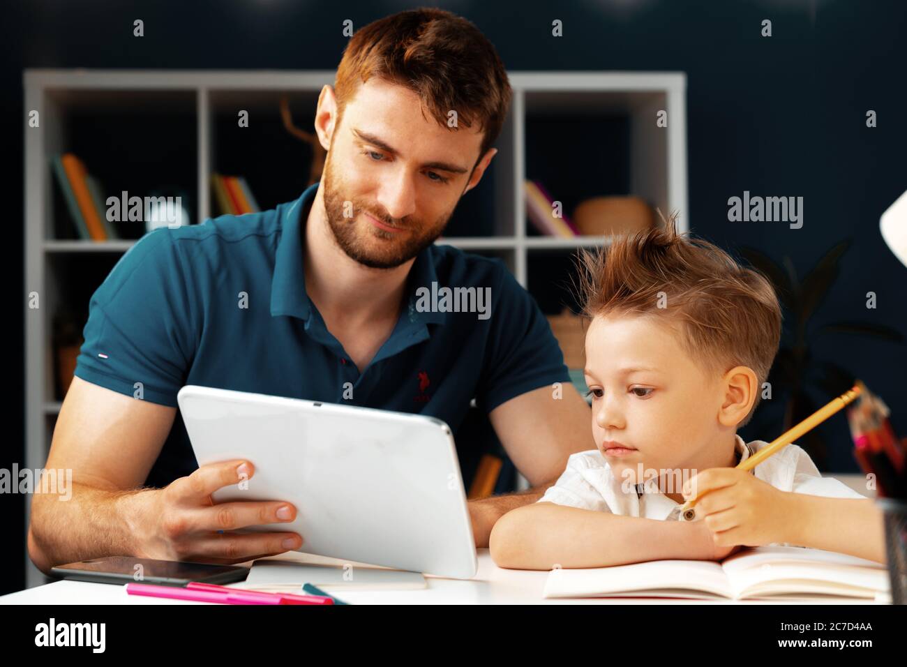 Young boy sitting with his father at the table and using laptop Stock ...