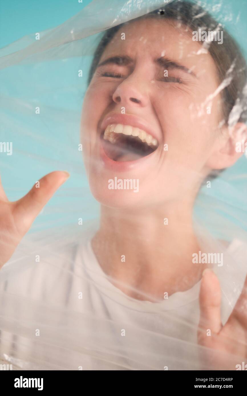 Frightened girl scaredly screaming in plastic bag over colorful ...