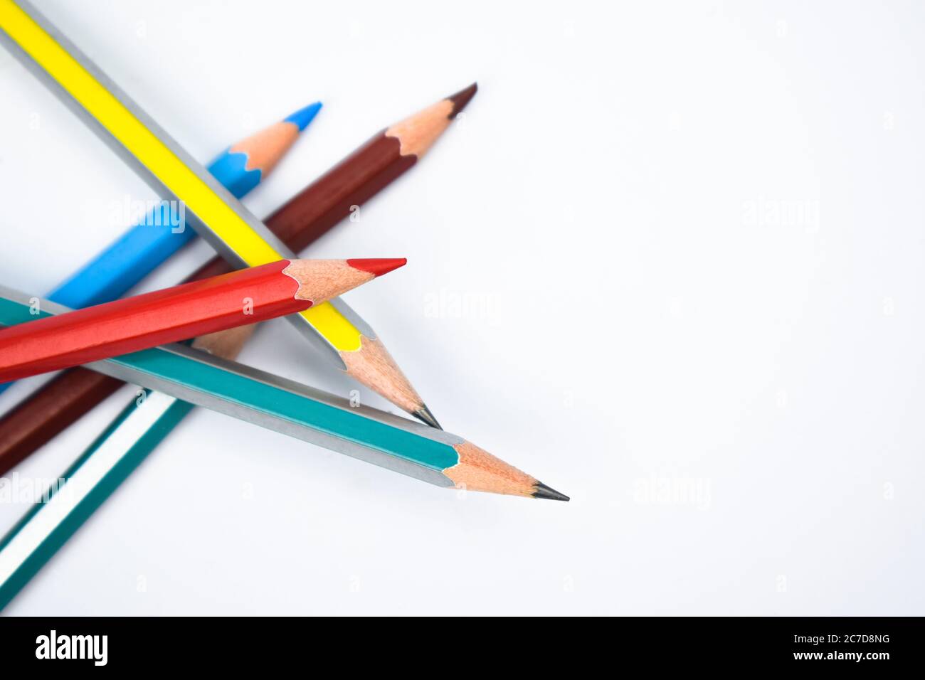 Some different colored wood pencil crayon scattered on a white paper background Stock Photo