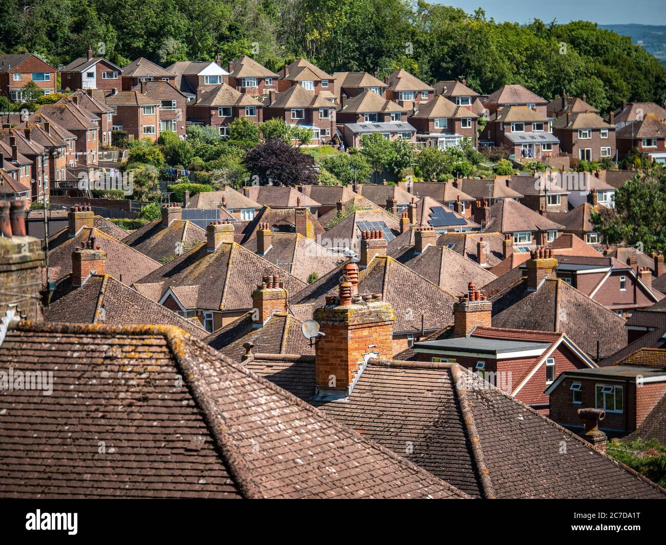 Suburban Rooftops. A view over the a post-war 1950's English housing estate on the fringes of Eastbourne backed by green belt ancient woodland. Stock Photo