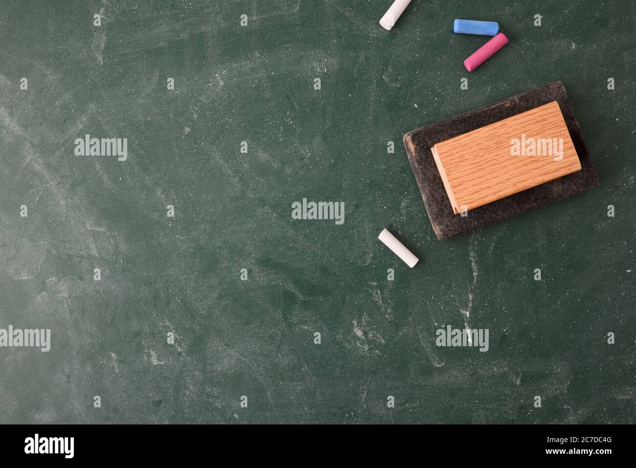 Erased and dirty class blackboard with white and colored chalk and eraser on top. Top view Stock Photo