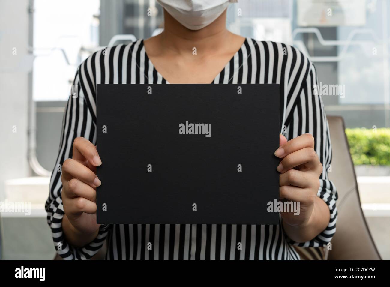 Female employee holding black chalk board sign wearing formal business attire Stock Photo