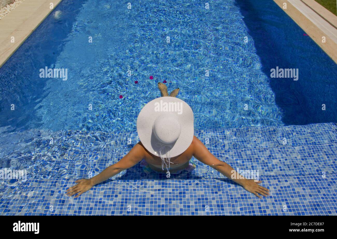 young woman in a white hat relaxing in the pool Stock Photo - Alamy