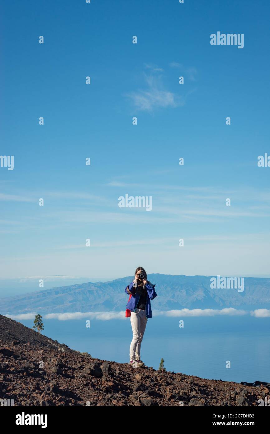 A woman taking a photo while hiking up Mount Teide in Tenerife, Canary Islands, Spain Stock Photo