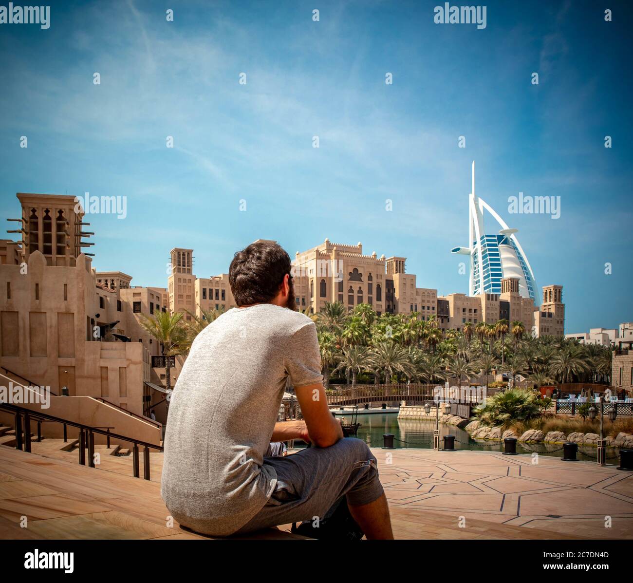 Person sitting on the stairs of Madinat Jumeirah Resort near Burj Al Arab in Dubai Stock Photo