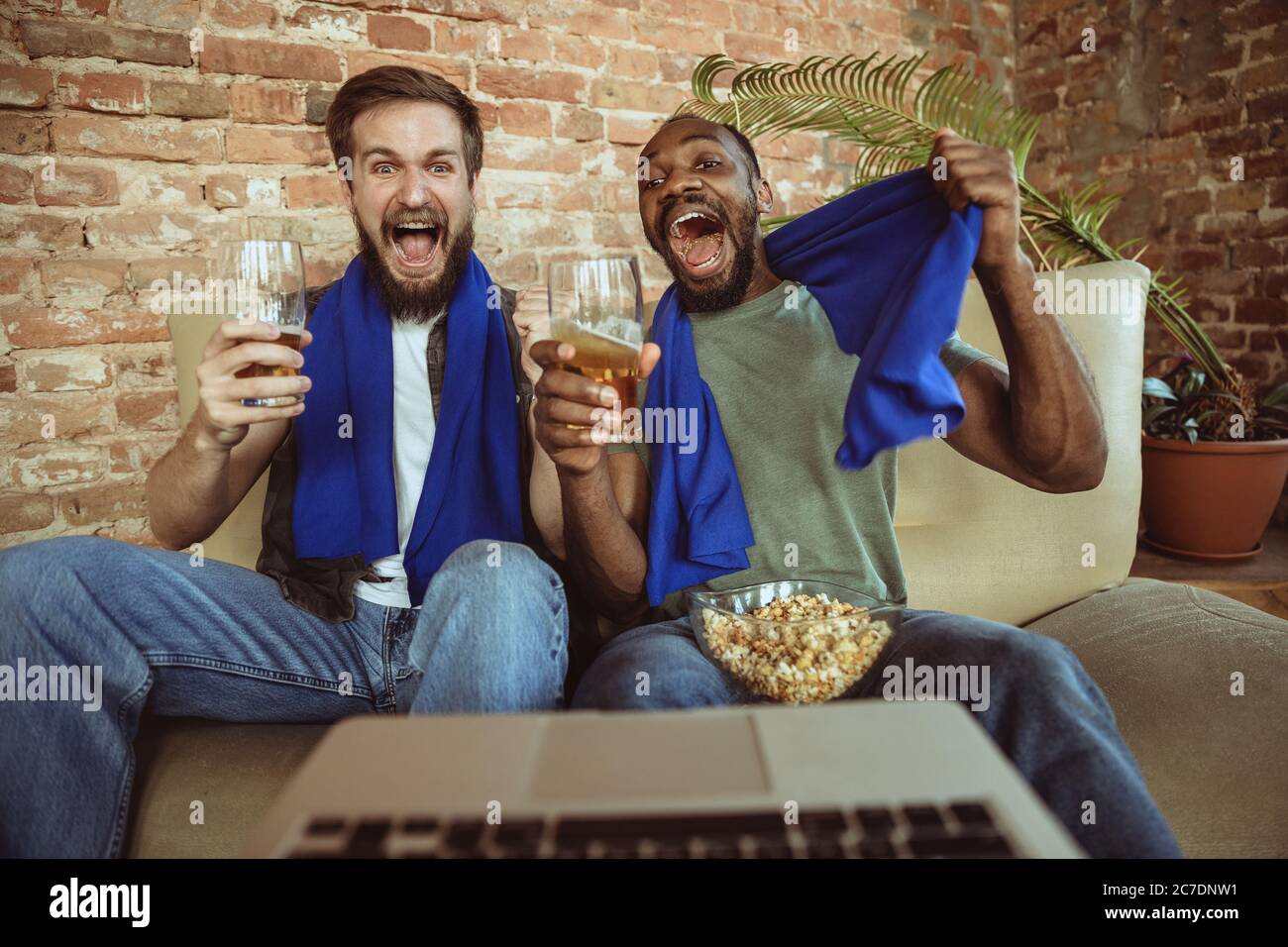 Excited football fans watching sport match at home, remote support of favourite team during