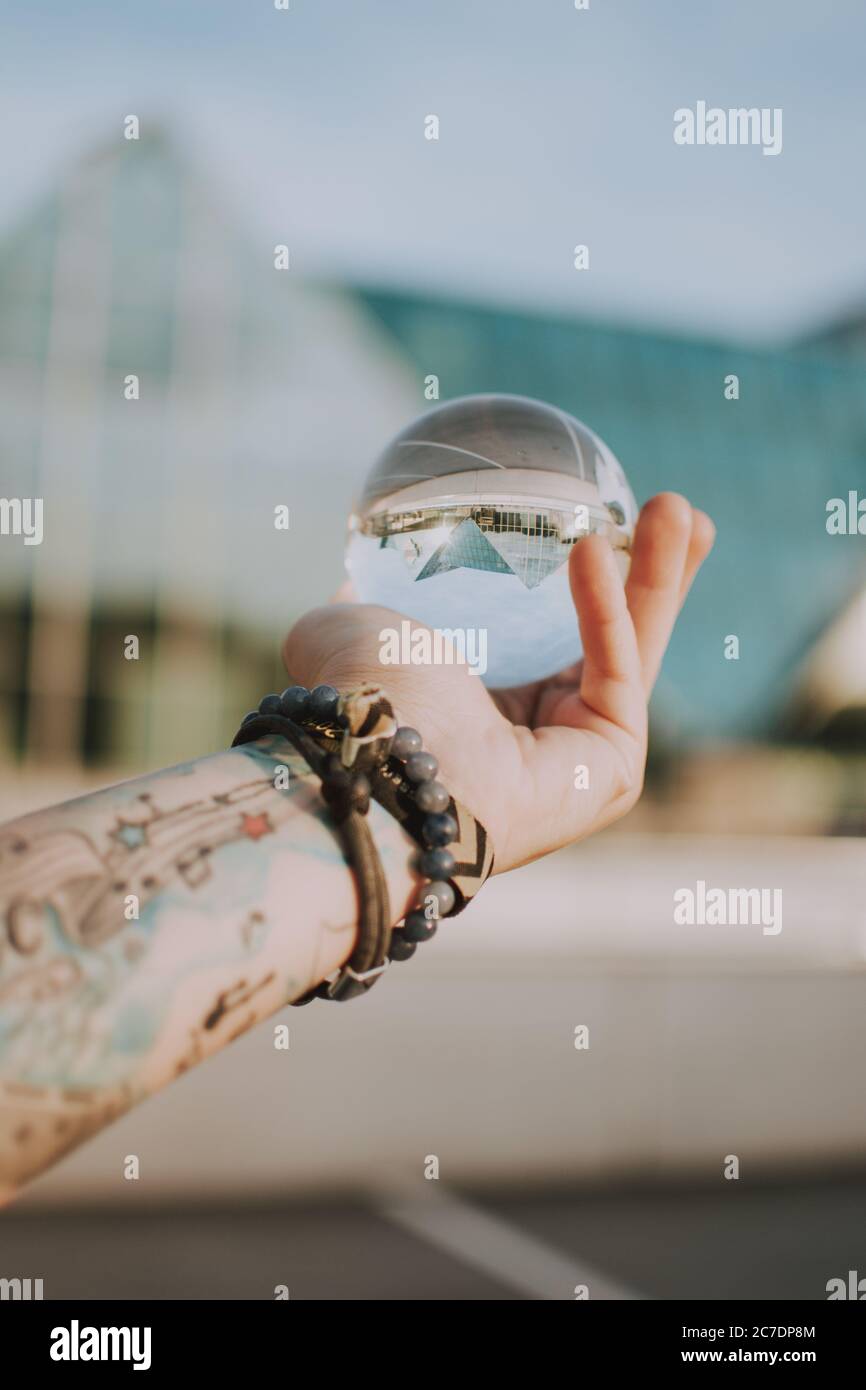 person holding a clear crystal glass ball with the reflection of a ...