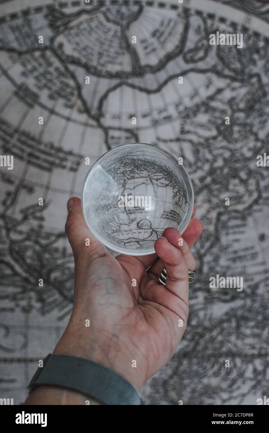 a person holding a clear crystal glass ball with the reflection of ...