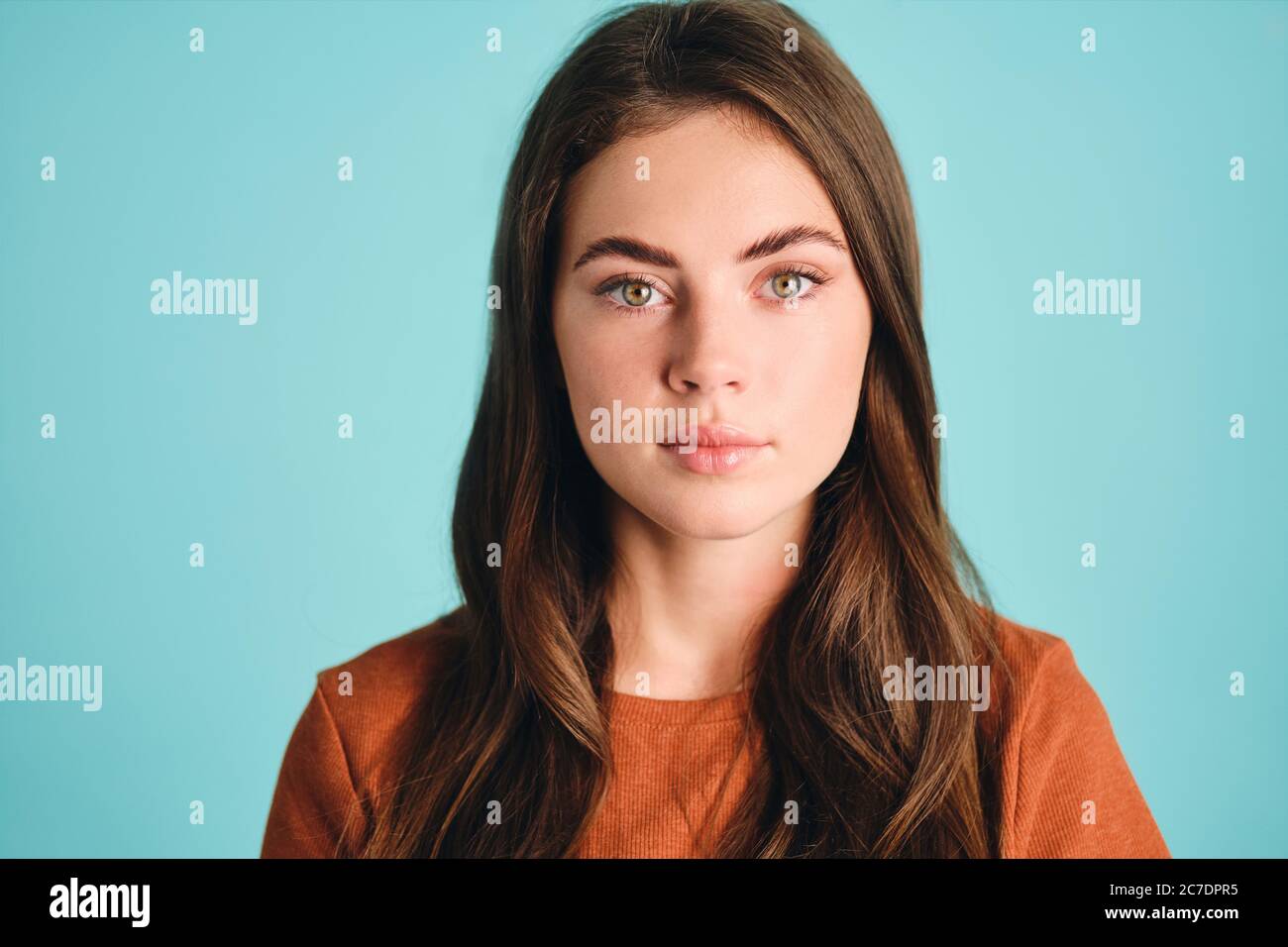 Close up beautiful brown haired girl confidently looking in camera over colorful background isolated Stock Photo