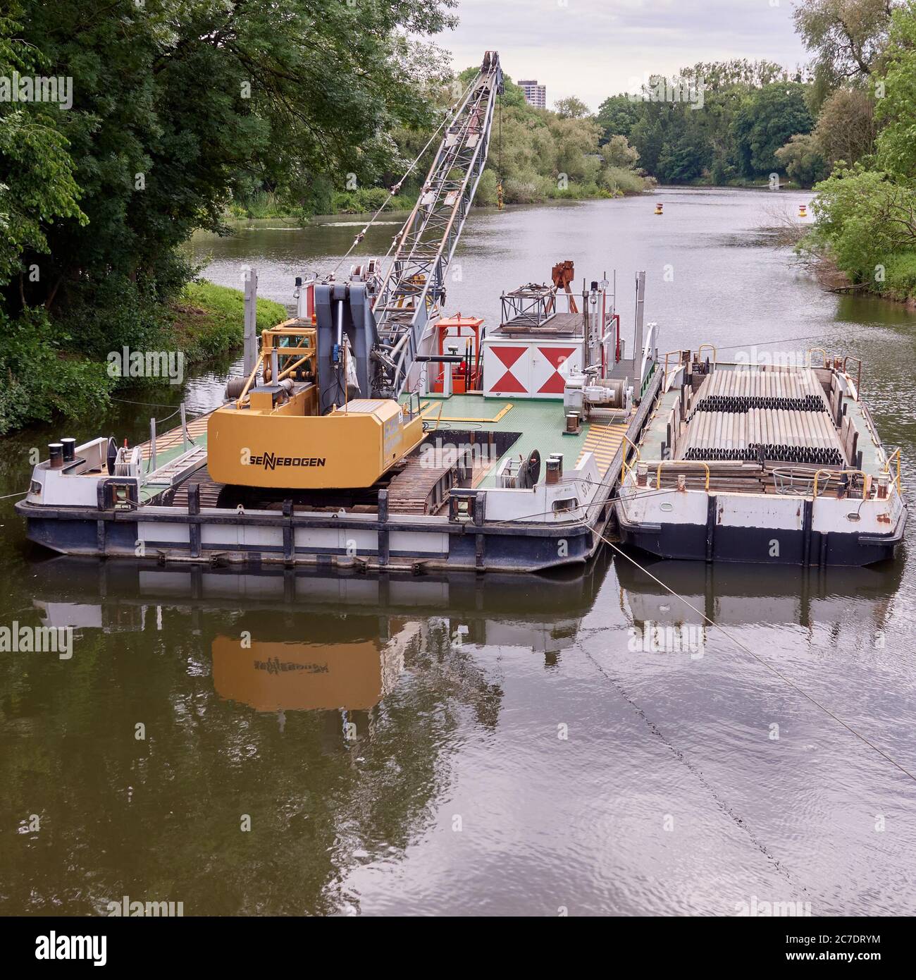 Hannover, Germany, May 30., 2020: Yellow excavator of the hydraulic engineering company Sennebogen on a pontoon during work on the canal Stock Photo