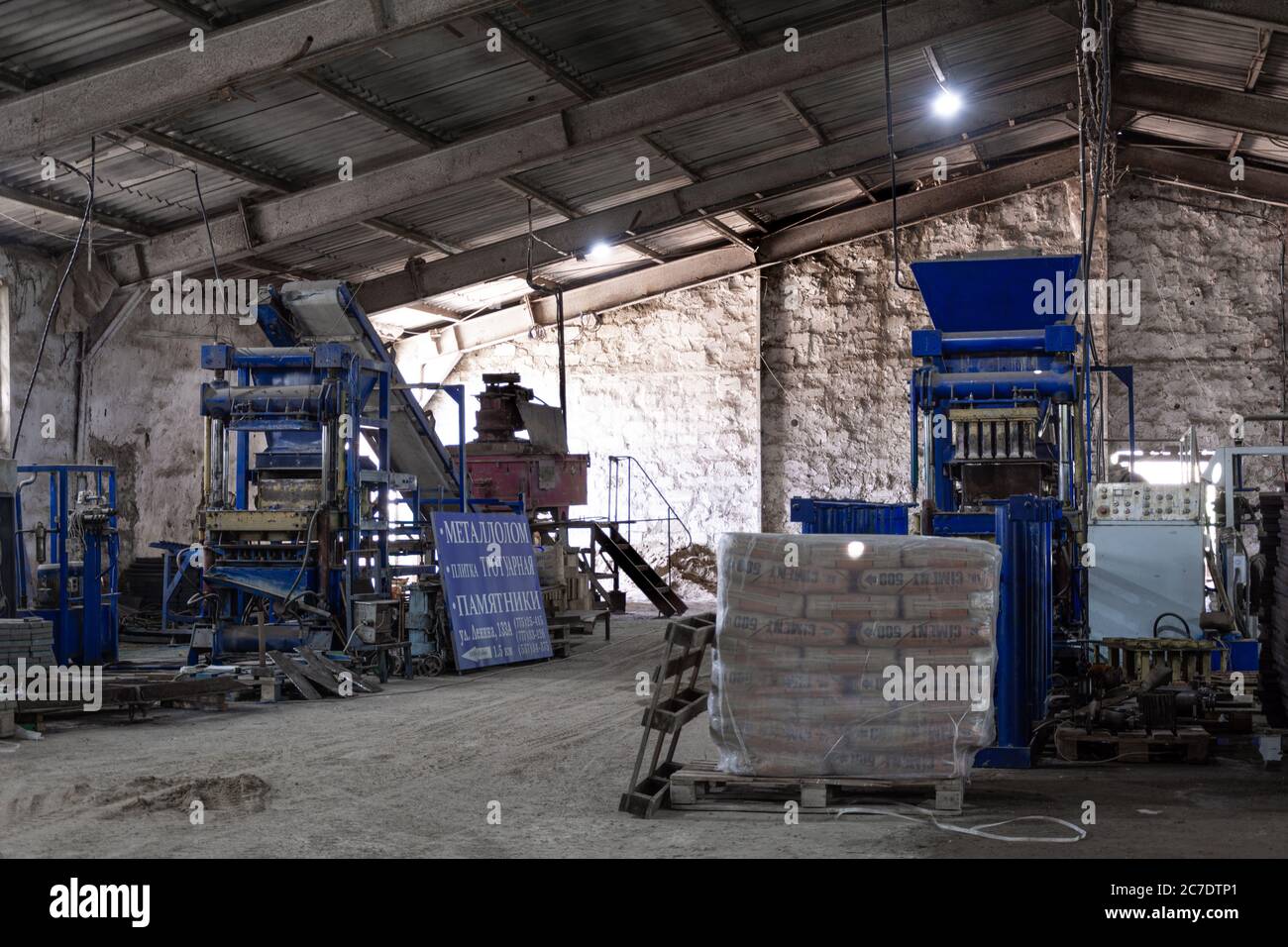 Bags of cement on a wooden pallet with the inscription 'Cement' on the paving slab factory. Workshop for the production of paving slabs. Stock Photo