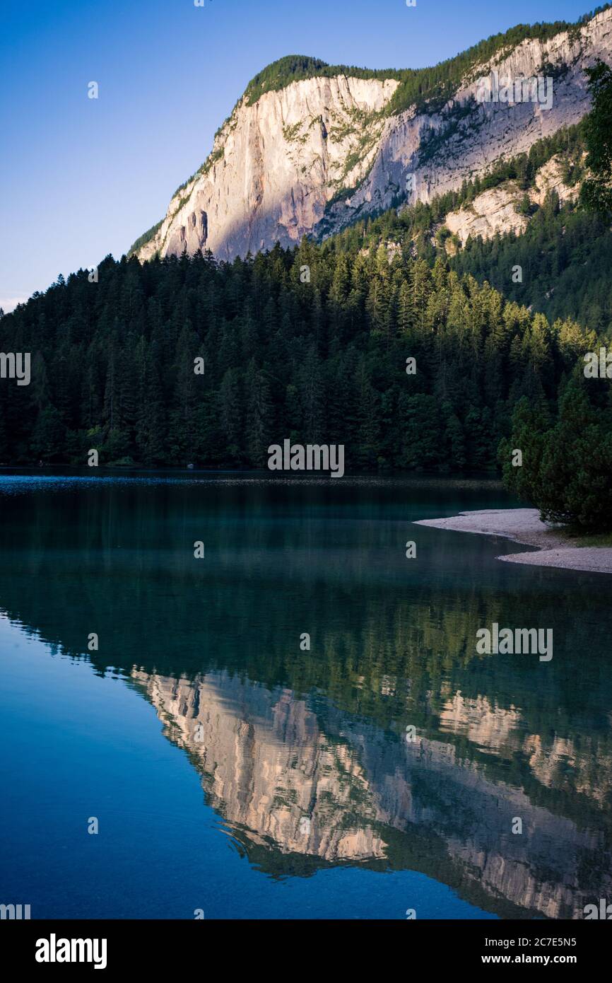 Vertical shot of a crystal clear lake near base of a white mountain ...