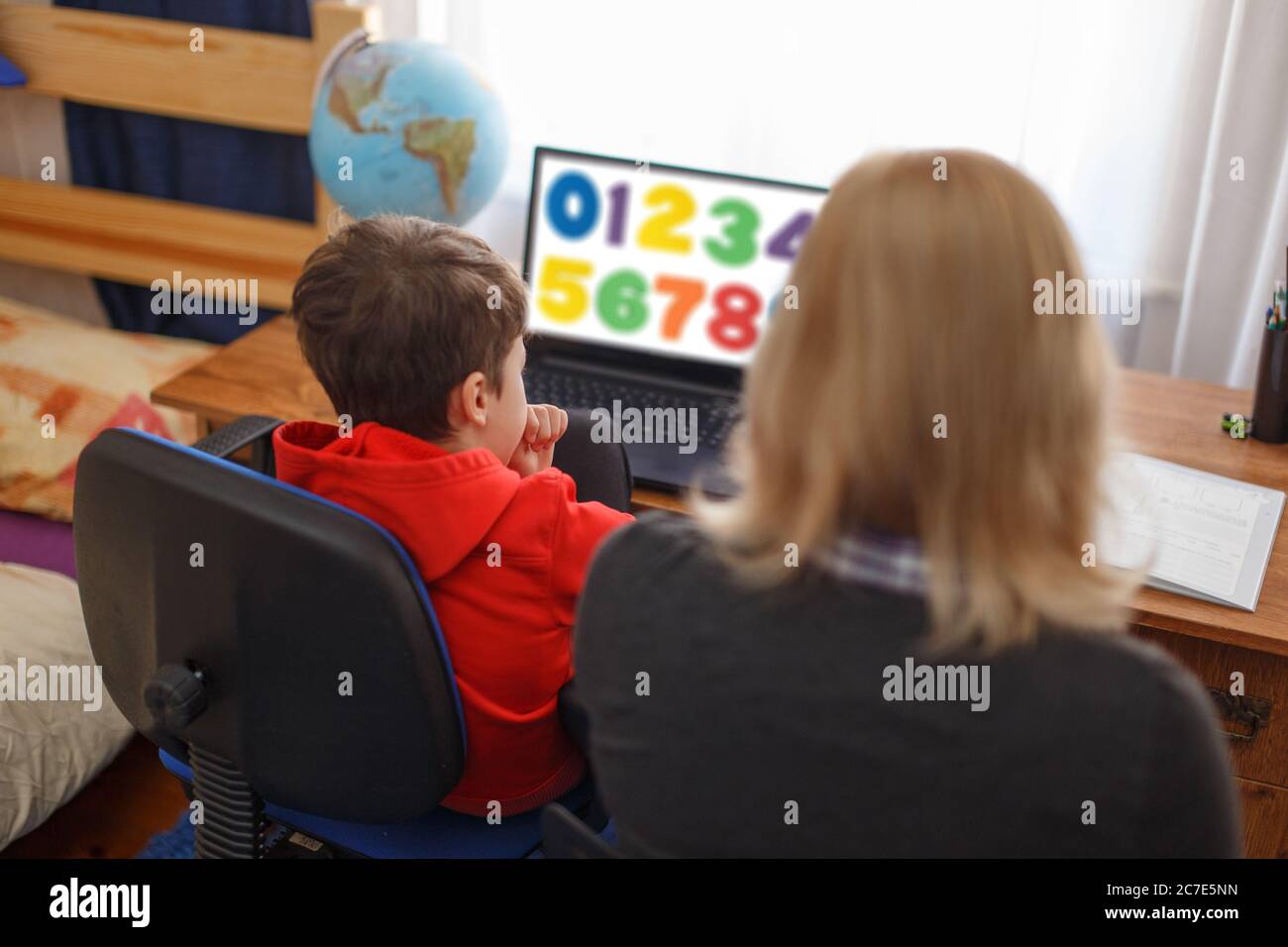 Mom helps learning maths on laptop to son at home Stock Photo