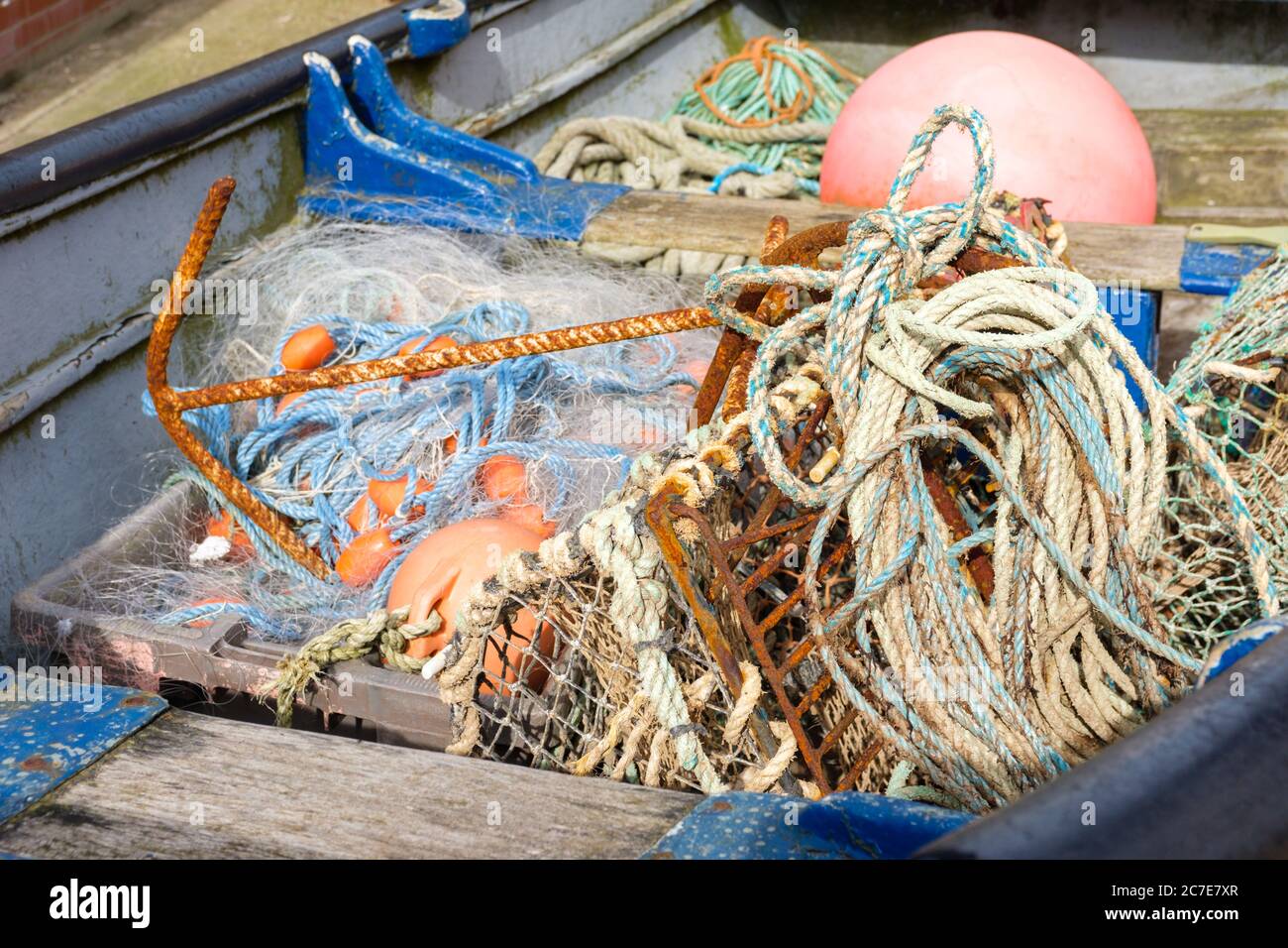 Fishing nets and tackle including lobster and crab pot, laying in a rowing boat. England, UK Stock Photo